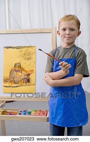 Portrait of a schoolboy holding a paintbrush and standing in an art class View Large Photo Image Stock Image - Portrait of a schoolboy holding a paintbrush and standing in an art class. Fotosearch
