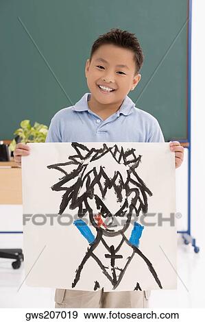 Stock Photo - Portrait of a schoolboy showing his drawing and smiling. Fotosearch