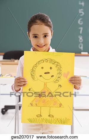 Stock Photo - Portrait of a schoolgirl showing her drawing and smiling. Fotosearch
