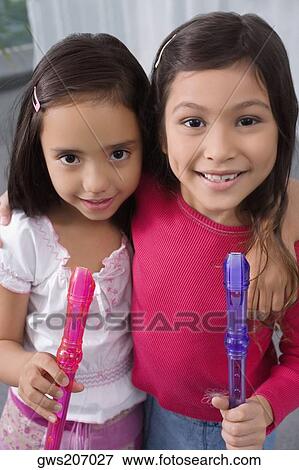 Portrait of two schoolgirls with their arms around each other and holding flutes View Large Photo Image Stock Photo - Portrait of two schoolgirls with their arms around each other and holding flutes. Fotosearch
