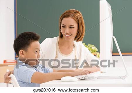 Side profile of a schoolboy with his teacher in front of a computer View Large Photo Image Stock Photograph - Side profile of a schoolboy with his teacher in front of a computer. Fotosearch