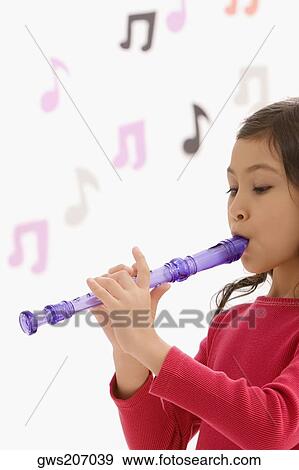 Stock Photo - Side profile of a schoolgirl playing a flute in a classroom. Fotosearch