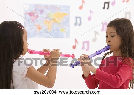 Side profile of two schoolgirls playing flutes in a classroom View Large Photo Image Picture - Side profile of two schoolgirls playing flutes in a classroom. Fotosearch