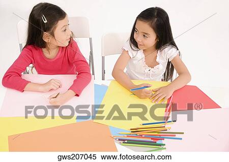 Two schoolgirls drawing in an art class and looking at each other View Large Photo Image Stock Photography - Two schoolgirls drawing in an art class and looking at each other. Fotosearch