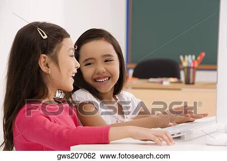 Two schoolgirls smiling in front of a computer View Large Photo Image Stock Image - Two schoolgirls smiling in front of a computer. Fotosearch