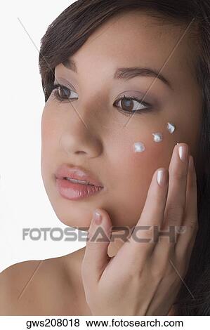 Close-up of a young woman applying cream on her face View Large Photo Image Stock Photo - Close-up of a young woman applying cream on her face. Fotosearch