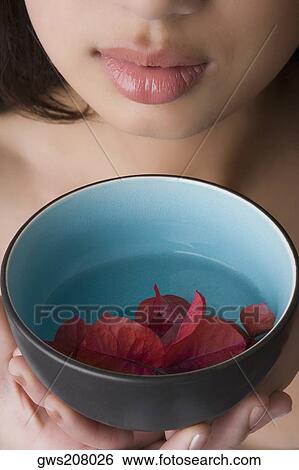 Close-up of a young woman holding a bowl of water with floating leaves View Large Photo Image Stock Photograph - Close-up of a young woman holding a bowl of water with floating leaves. Fotosearch