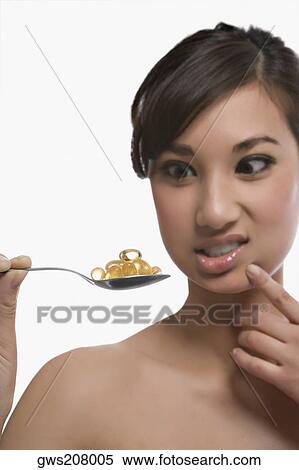 Close-up of a young woman holding a spoon of pills View Large Photo Image Stock Photography - Close-up of a young woman holding a spoon of pills. Fotosearch