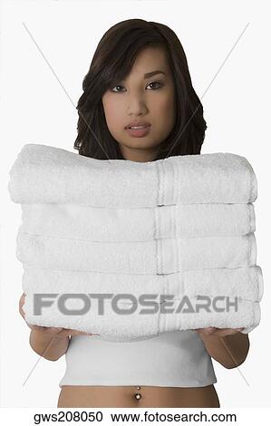 Portrait of a young woman holding a stack of folded towels View Large Photo Image Stock Image - Portrait of a young woman holding a stack of folded towels. Fotosearch