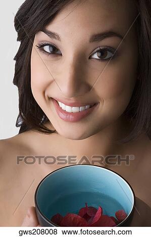 Portrait of a young woman holding a bowl of water with floating leaves View Large Photo Image Stock Photo - Portrait of a young woman holding a bowl of water with floating leaves. Fotosearch