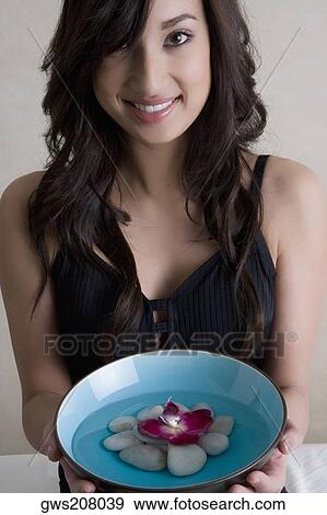 Portrait of a young woman holding a bowl of water with stones and a rose View Large Photo Image Stock Photo - Portrait of a young woman holding a bowl of water with stones and a rose. Fotosearch