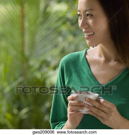 Close-up of a young woman holding a cup of tea and smiling View Large Photo Image Stock Photograph - Close-up of a young woman holding a cup of tea and smiling. Fotosearch