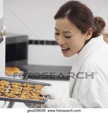 Close-up of a young woman holding a tray of cookies and smiling View Large Photo Image Stock Photo - Close-up of a young woman holding a tray of cookies and smiling. Fotosearch