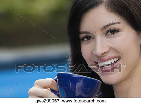 Stock Photo - Portrait of a young woman drinking tea and smiling. Fotosearch