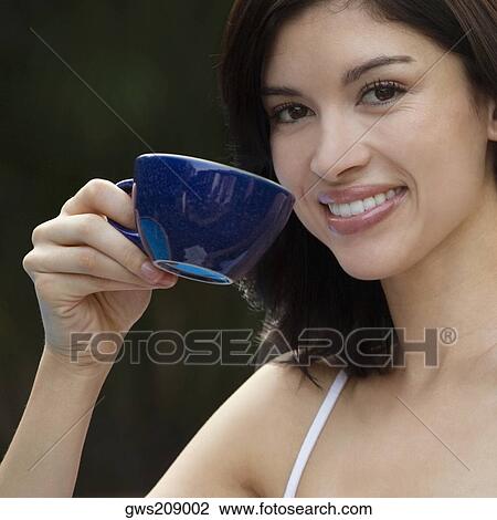 Stock Image - Portrait of a young woman holding a cup of tea and smiling. Fotosearch