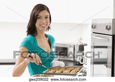 Portrait of a young woman holding a tray of cookies and smiling View Large Photo Image Stock Image - Portrait of a young woman holding a tray of cookies and smiling. Fotosearch