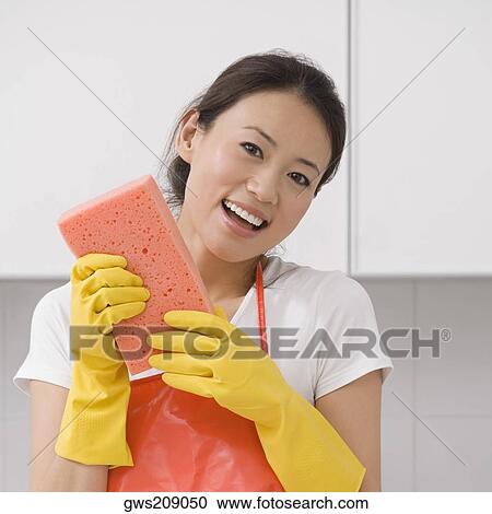 Stock Image - Portrait of a young woman holding a bath sponge and smiling. Fotosearch
