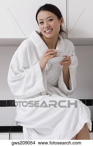 Portrait of a young woman wearing a bathrobe and drinking tea View Large Photo Image Picture - Portrait of a young woman wearing a bathrobe and drinking tea. Fotosearch