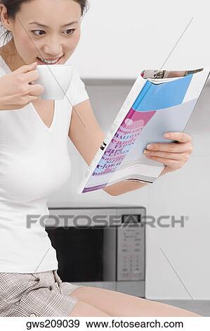 Side profile of a young woman drinking tea and reading a magazine View Large Photo Image Stock Photo - Side profile of a young woman drinking tea and reading a magazine. Fotosearch