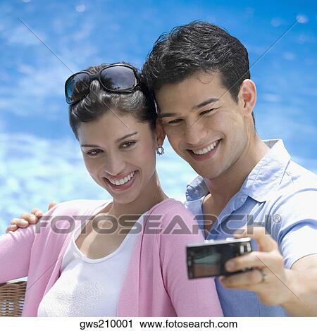 Stock Image - Close-up of a young couple taking a picture of themselves. Fotosearch