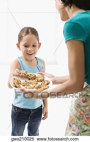Close-up of a young woman serving cookies to her daughter View Large Photo Image Stock Photography - Close-up of a young woman serving cookies to her daughter. Fotosearch