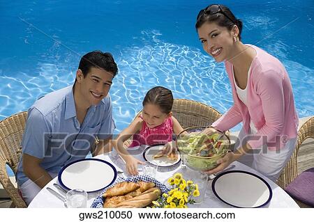 Portrait of a young couple eating breakfast with their daughter View Large Photo Image Stock Image - Portrait of a young couple eating breakfast with their daughter. Fotosearch