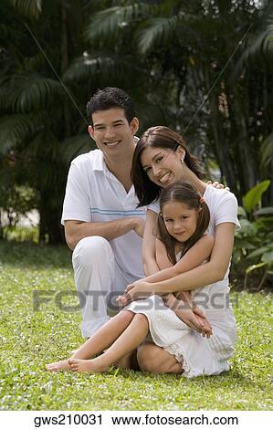 Portrait of a young couple with their daughter sitting in a garden View Large Photo Image Stock Image - Portrait of a young couple with their daughter sitting in a garden. Fotosearch