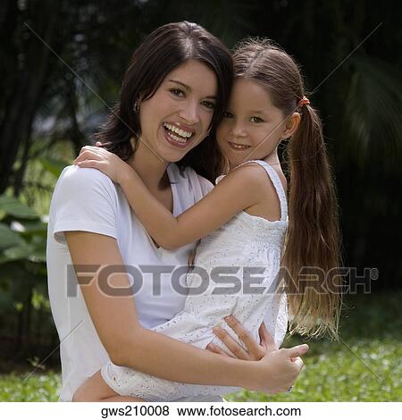Portrait of a young woman carrying her daughter and smiling View Large Photo Image Stock Photo - Portrait of a young woman carrying her daughter and smiling. Fotosearch