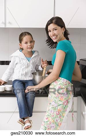 Portrait of a young woman smiling with her daughter in a kitchen View Large Photo Image Stock Image - Portrait of a young woman smiling with her daughter in a kitchen. Fotosearch