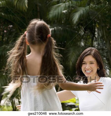 Rear view of a girl running to hug her mother in a park View Large Photo Image Stock Photograph - Rear view of a girl running to hug her mother in a park. Fotosearch