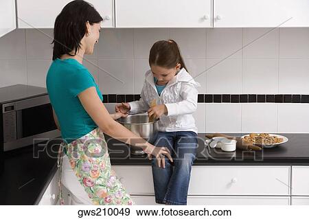 Side profile of a young woman preparing food with her daughter in the kitchen View Large Photo Image Stock Photo - Side profile of a young woman preparing food with her daughter in the kitchen. Fotosearch