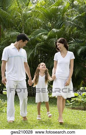 Young couple walking with their daughter in a garden View Large Photo Image Stock Photo - Young couple walking with their daughter in a garden. Fotosearch