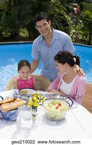 Stock Image - Young couple with their daughter at a breakfast table and smiling. Fotosearch