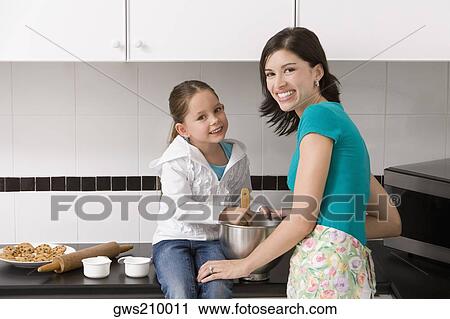 Stock Image - Young woman making cookies with her daughter in the kitchen. Fotosearch