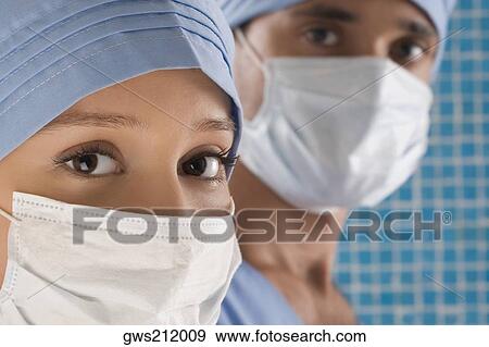 Close-up of a female doctor and a male doctor wearing surgical masks View Large Photo Image Stock Photo - Close-up of a female doctor and a male doctor wearing surgical masks. Fotosearch