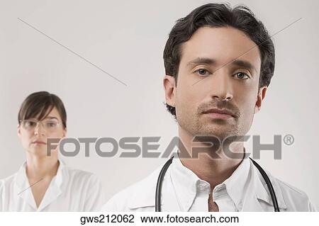 Close-up of a male doctor with a female doctor behind him View Large Photo Image Stock Image - Close-up of a male doctor with a female doctor behind him. Fotosearch