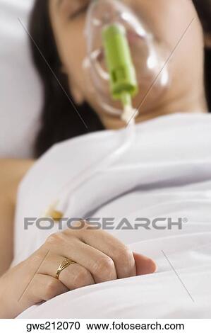 Stock Image - Close-up of a young woman wearing an oxygen mask. Fotosearch