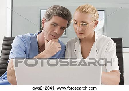 Stock Image - Female doctor and a male surgeon sitting in a clinic. Fotosearch