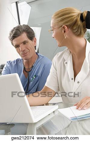 Female doctor discussing with a male surgeon at a clinic View Large Photo Image Picture - Female doctor discussing with a male surgeon at a clinic. Fotosearch