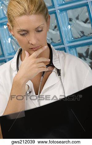 Female doctor examining an X-Ray report View Large Photo Image Stock Photo - Female doctor examining an X-Ray report. Fotosearch