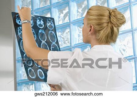 Stock Photograph - Female doctor examining an X-Ray report. Fotosearch