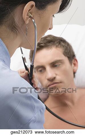 Stock Image - Female surgeon examining a mid adult man. Fotosearch