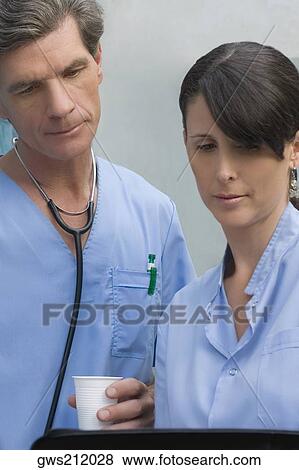 Male surgeon and a female surgeon looking at a medical record View Large Photo Image Stock Photo - Male surgeon and a female surgeon looking at a medical record. Fotosearch