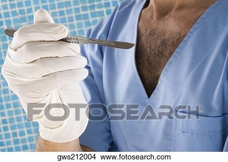 Mid section view of a male surgeon holding a scalpel View Large Photo Image Picture - Mid section view of a male surgeon holding a scalpel. Fotosearch