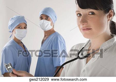 Portrait of a female doctor with two surgeons in the background View Large Photo Image Stock Photo - Portrait of a female doctor with two surgeons in the background. Fotosearch