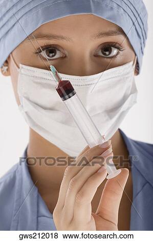 Stock Photo - Portrait of a female surgeon holding a syringe. Fotosearch