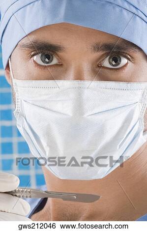 Stock Photograph - Portrait of a male surgeon holding a scalpel. Fotosearch