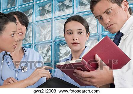 Stock Photo - Three male surgeons and a male doctor discussing a medical report. Fotosearch