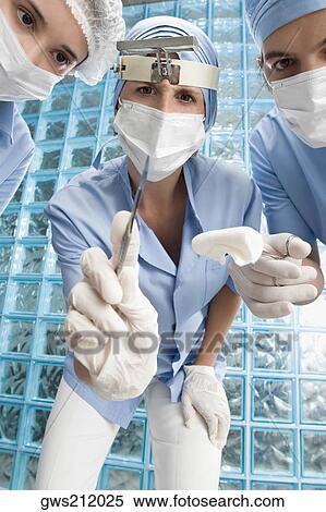 Two female surgeons and a male surgeon in an operating room View Large Photo Image Stock Photography - Two female surgeons and a male surgeon in an operating room. Fotosearch