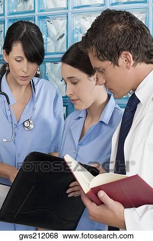 Two male surgeons and a male doctor discussing a medical report View Large Photo Image Stock Photo - Two male surgeons and a male doctor discussing a medical report. Fotosearch